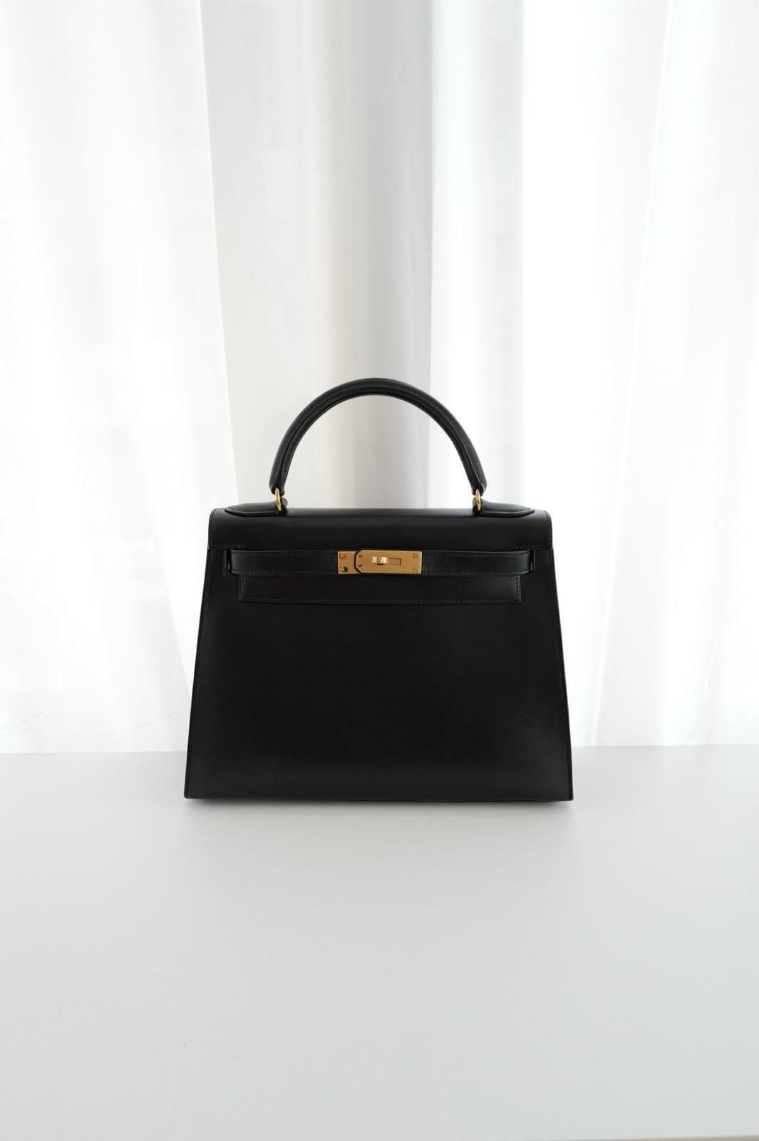 Black handbag with gold clasp on a white background