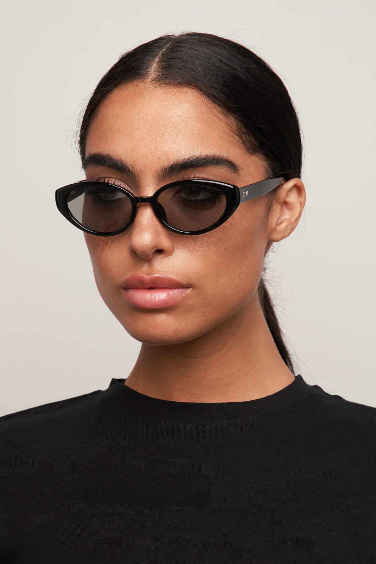 Model wearing Greta black cat-eye sunglasses, side view