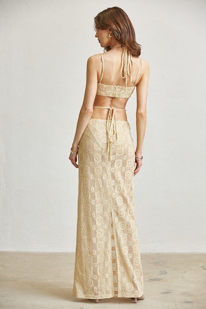 Back view of a model wearing an ISSUE 92 beige lace maxi dress with bead details and a tie-back crop top