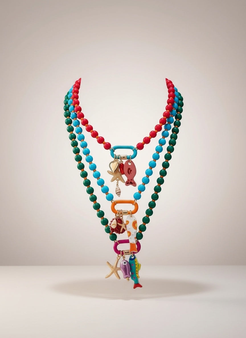 ISSUE 92 layered beaded necklaces in red, turquoise, and green with ocean-themed charms like fish, starfish, and shells.