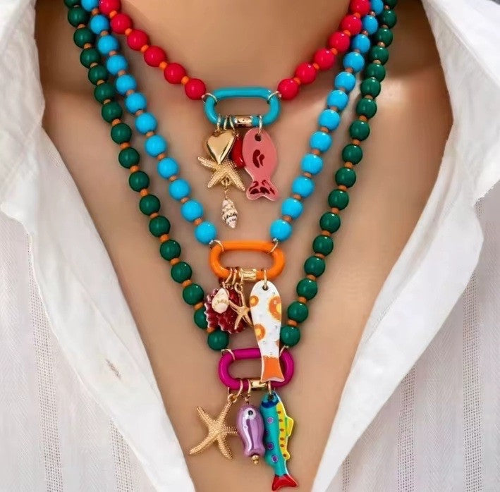 ISSUE 92 layered beaded necklaces with fish, starfish, and shell charms in red, blue, green, and orange.