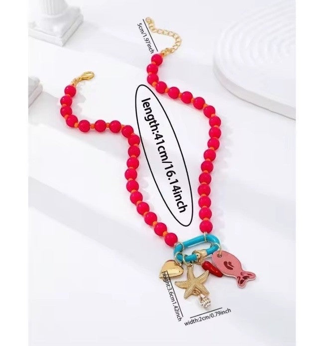 ISSUE 92 red beaded necklace with starfish, heart, chili pepper, and fish charms on a blue ring.